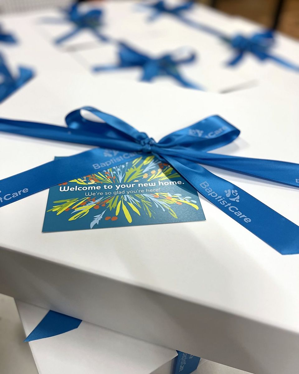Gift boxes tied with branded blue ribbon and a custom printed welcome card