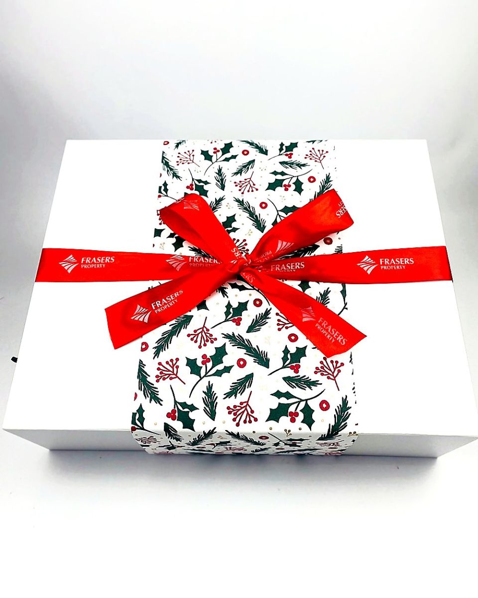 White gift box with a Christmas print band and branded red ribbon