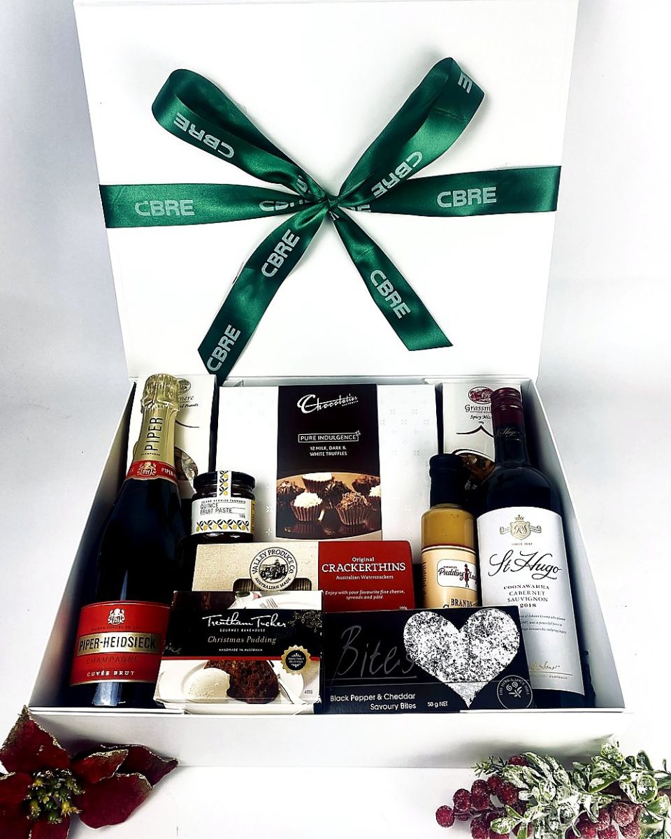 Christmas hamper with Champagne, red wine and pudding under a branded green ribbon