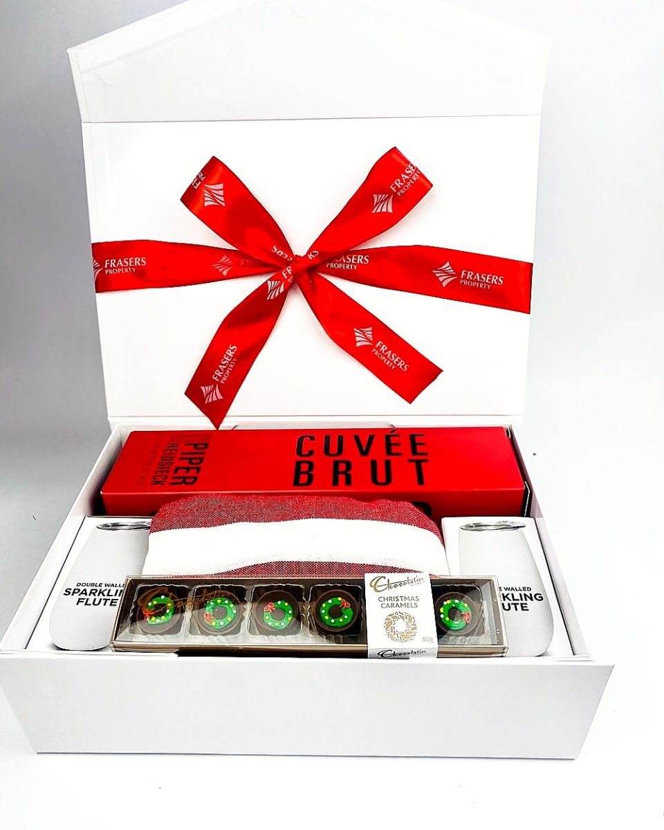 White gift box with a client-branded red ribbon, holding Piper-Heidsieck Champagne, flutes and Christmas caramels